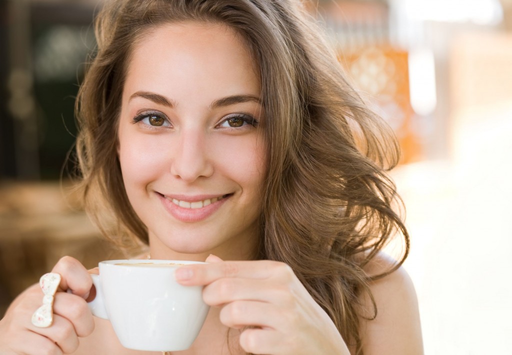14838408 - portrait of a beautiful young brunette woman enjoying coffee.
