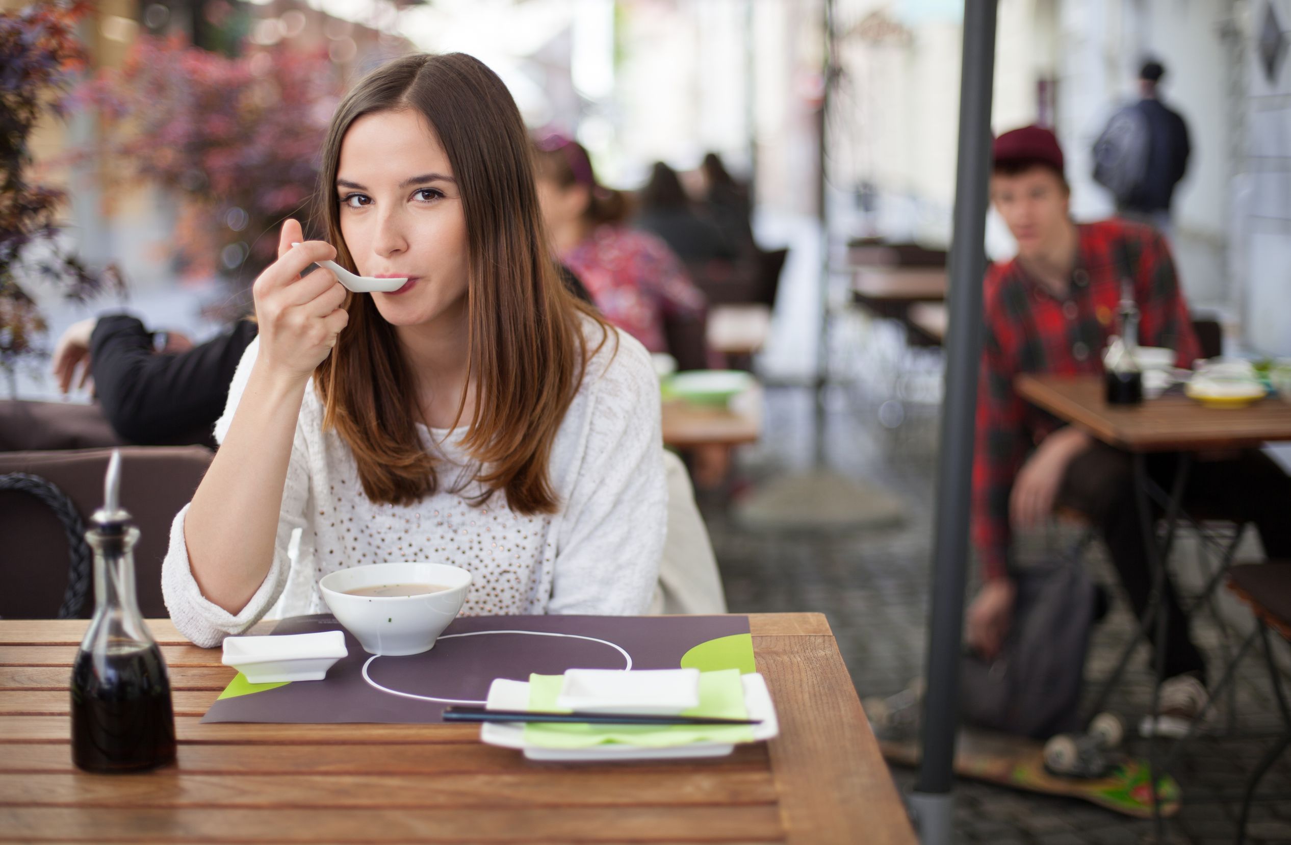 19754646 - young woman eating soup in an restaurant garden