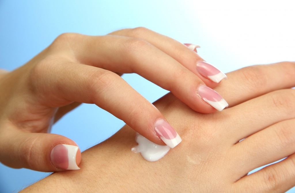 15958817 - beautiful woman hands with cream, on blue background