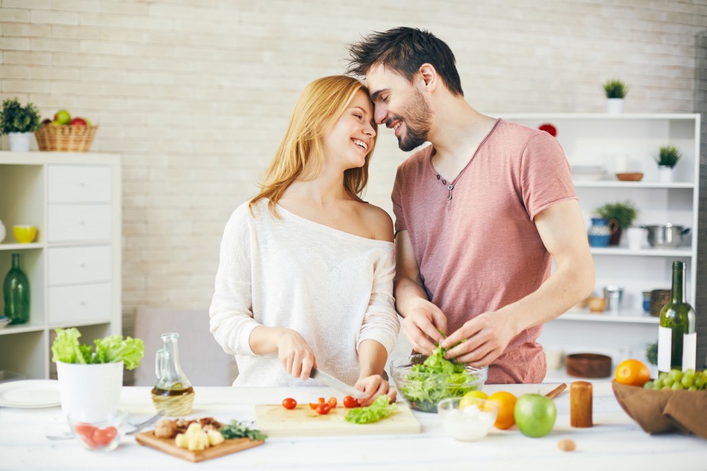 49526157 - young couple cooking fresh vegetarian salad together