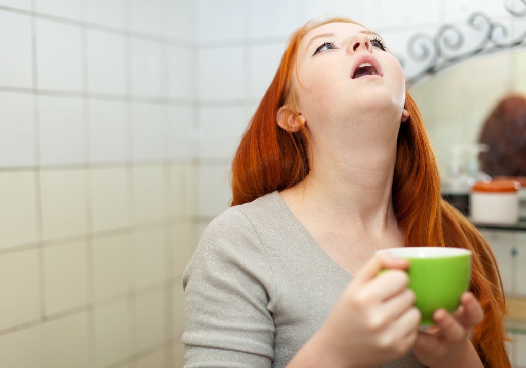 21999799 - red-haired teenager gargling throat in her bathroom at home