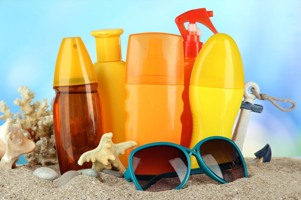 22252315 - bottles with suntan cream and sunglasses, on blue background